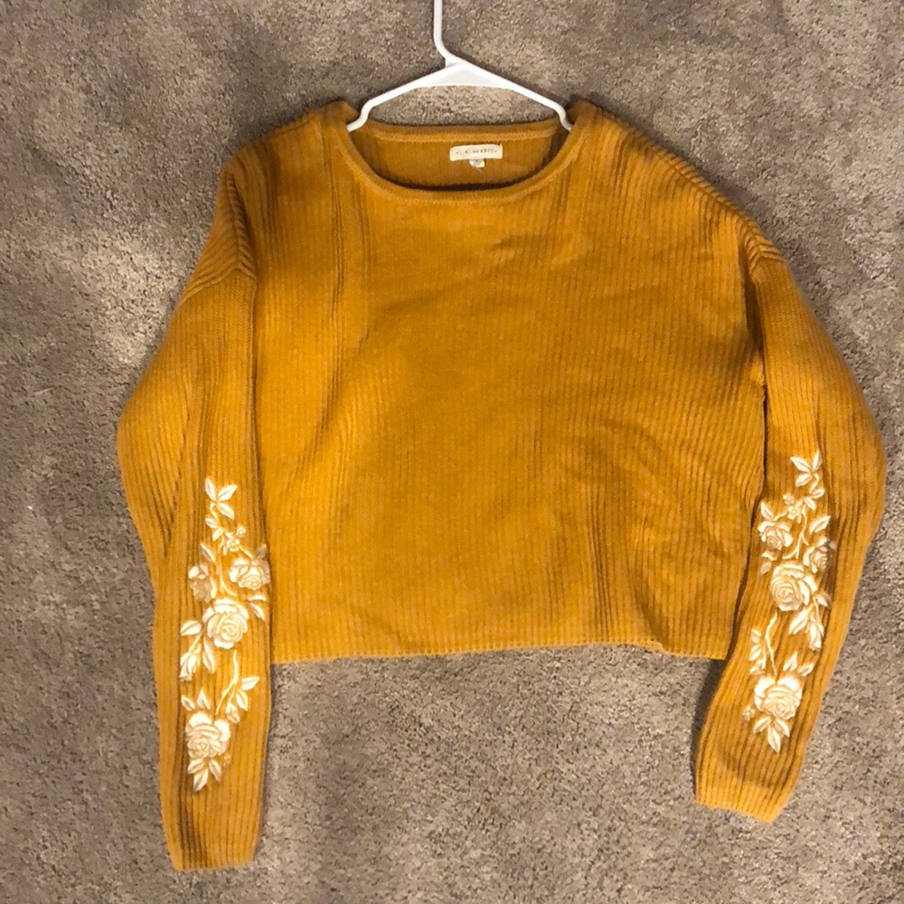 A yellow sweater with white embroidered flowers